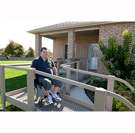Ramps - a man in a wheelchair on a safety ramp outside of his home. Ramps